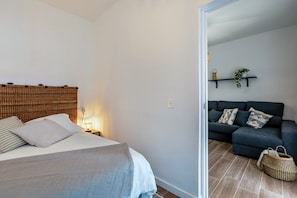 A bedroom with a bed, bedside table, and a nightstand with a lamp.