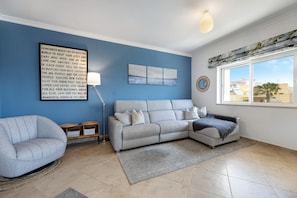 Una sala de estar con un sofá, un sillón y una pared con una cita motivacional.