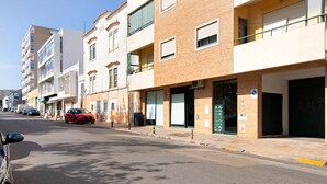 A street view with multi-story buildings, a red car parked on the side, and a clear sky. - Apartment "Sunset House Algarve" with Private Terrace & Wi-Fi (Faro)