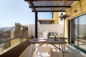 A balcony with a table, chairs, a hammock, and a view of the city. - Apartment "Sunset House Algarve" with Private Terrace & Wi-Fi (Faro)