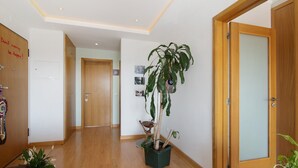 A hallway with wooden flooring, a potted plant, a wooden door, and a white wall with a picture. - Apartment "Sunset House Algarve" with Private Terrace & Wi-Fi (Faro)