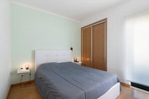 Une chambre à coucher avec un lit, une table de chevet, une lampe et une porte coulissante.