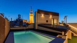 Una piscina en la azotea con vistas a una torre histórica y edificios modernos.