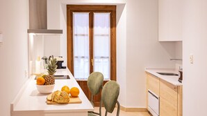 Una cocina compacta con puerta de madera, armarios blancos, encimera blanca y un lavamanos pequeño.