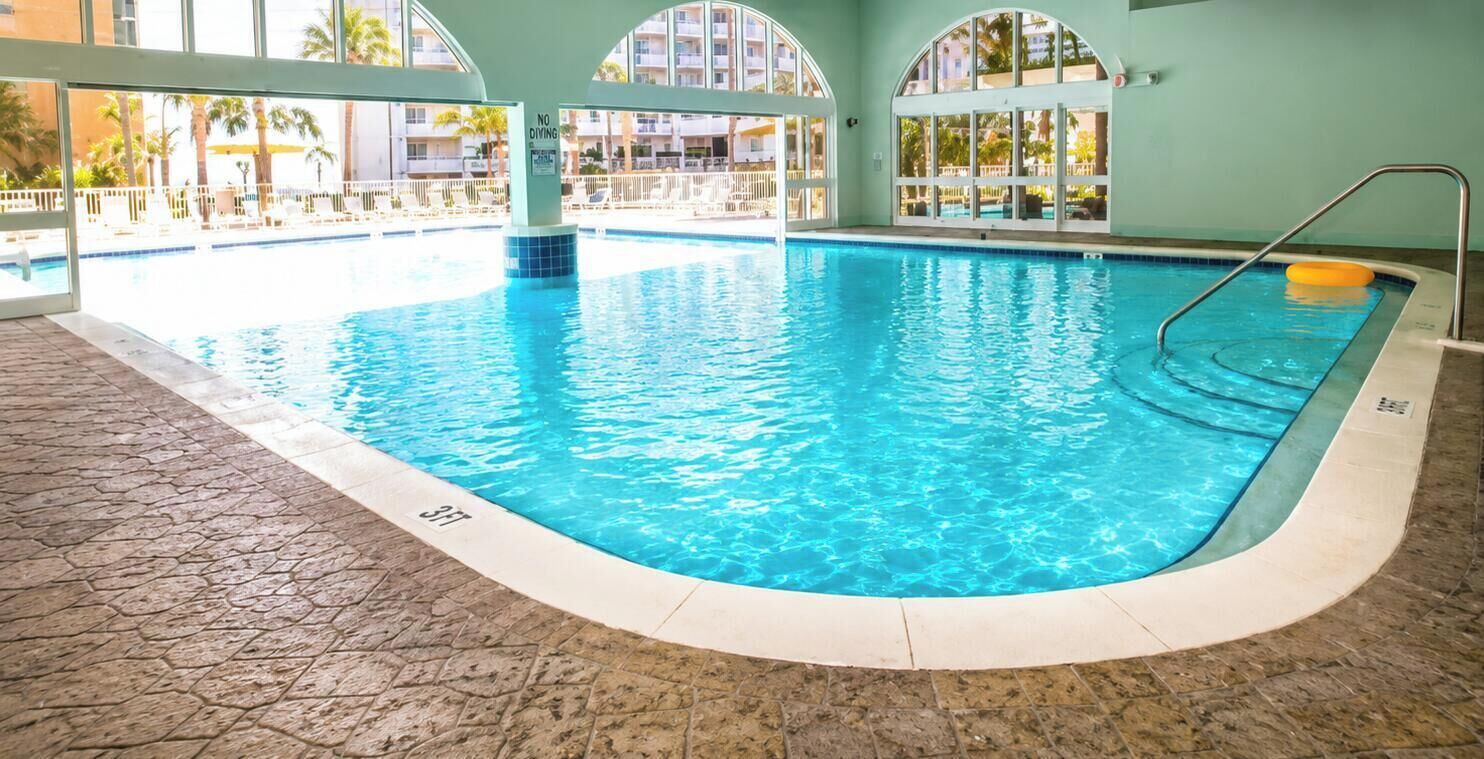 Une piscine intérieure à l’eau claire, dotée d’un sol carrelé et d’un panneau indiquant qu’il est interdit de plonger.