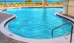 A swimming pool with a 8' depth marker, surrounded by lounge chairs and a view of the ocean. - OCEAN STAR SUITE @Celadon Beach Resort-OCEANFRONT (Panama City Beach)