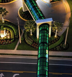 A modern building with a curved glass facade, a green cylindrical structure, and landscaped gardens with palm trees. - OCEAN STAR SUITE @Celadon Beach Resort-OCEANFRONT (Panama City Beach)
