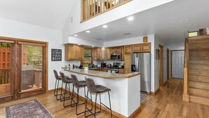 Une cuisine spacieuse dotée d’un îlot central, de meubles en bois et d’un plafond haut.