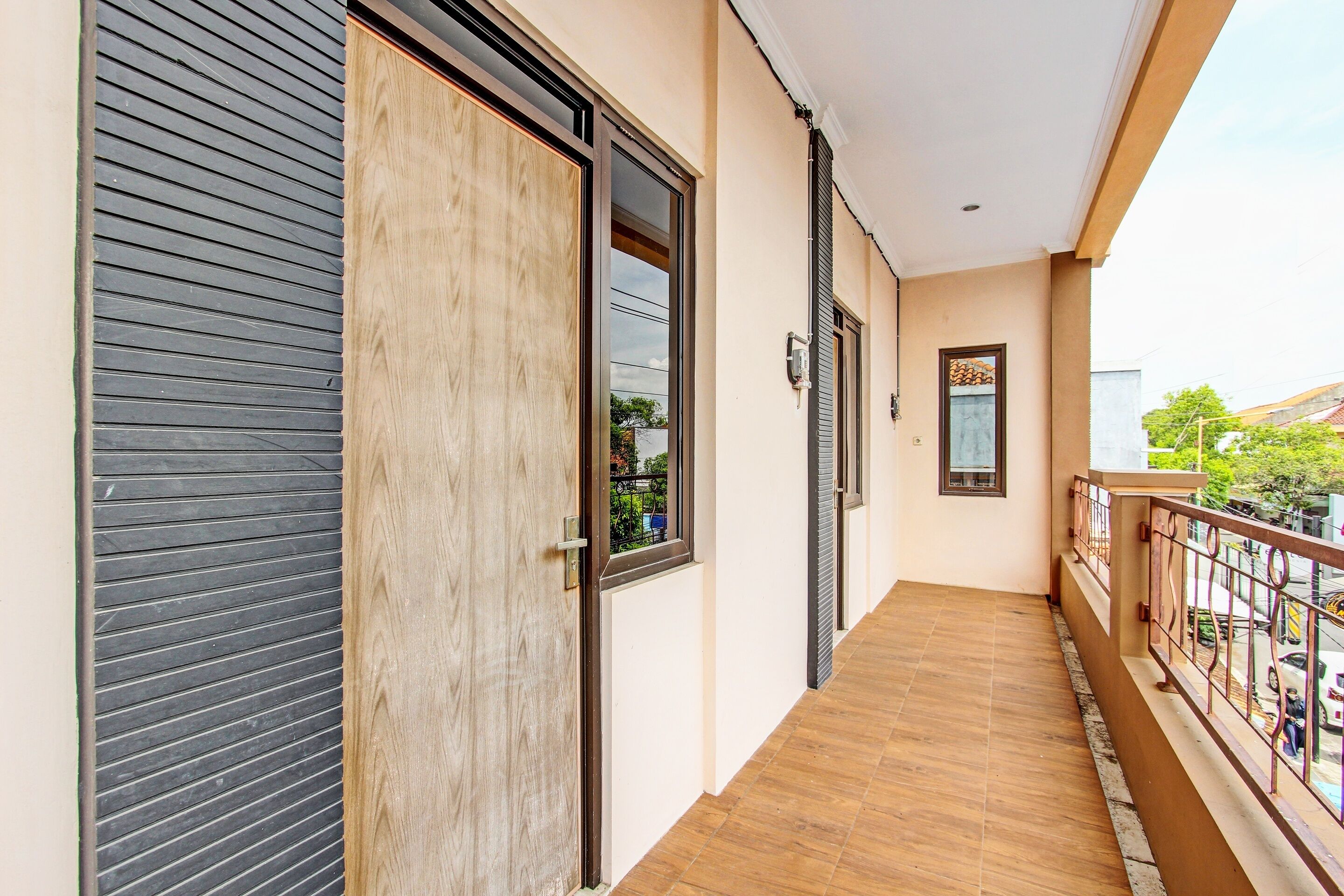 A corridor with a wooden door, a window, and a balcony with a railing.