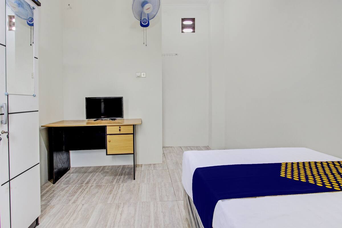 A bedroom with a bed, a desk, and a chair.