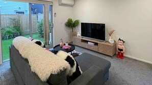 A modern living room with a grey sofa, a flat-screen TV, and a small table with decorative items.