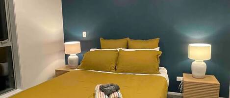 A bedroom with a bed, two bedside tables, and a window.