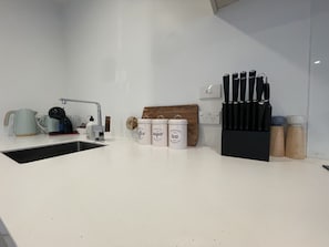 Enjoy cooking in this well-organized kitchen with a coffee maker, knife block, and cutting board.