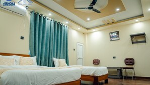 A hotel room with two beds, a ceiling fan, a desk, and a chair. - Hotel Happy Home (Siddharthanagar)