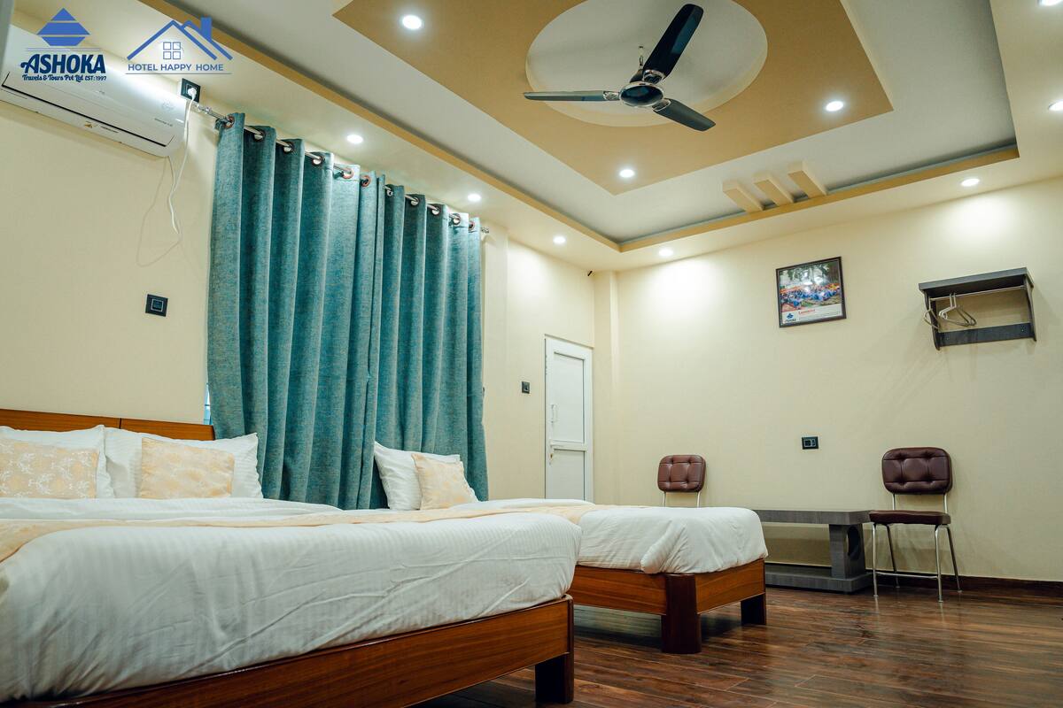 A hotel room with two beds, a ceiling fan, a desk, and a chair.