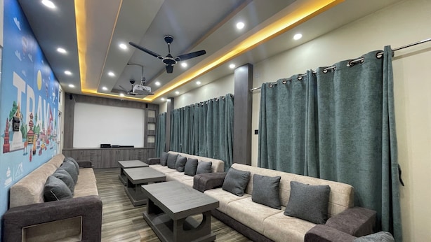 A modern home theater with a large screen, comfortable seating, and a ceiling fan. - Hotel Happy Home (Siddharthanagar)