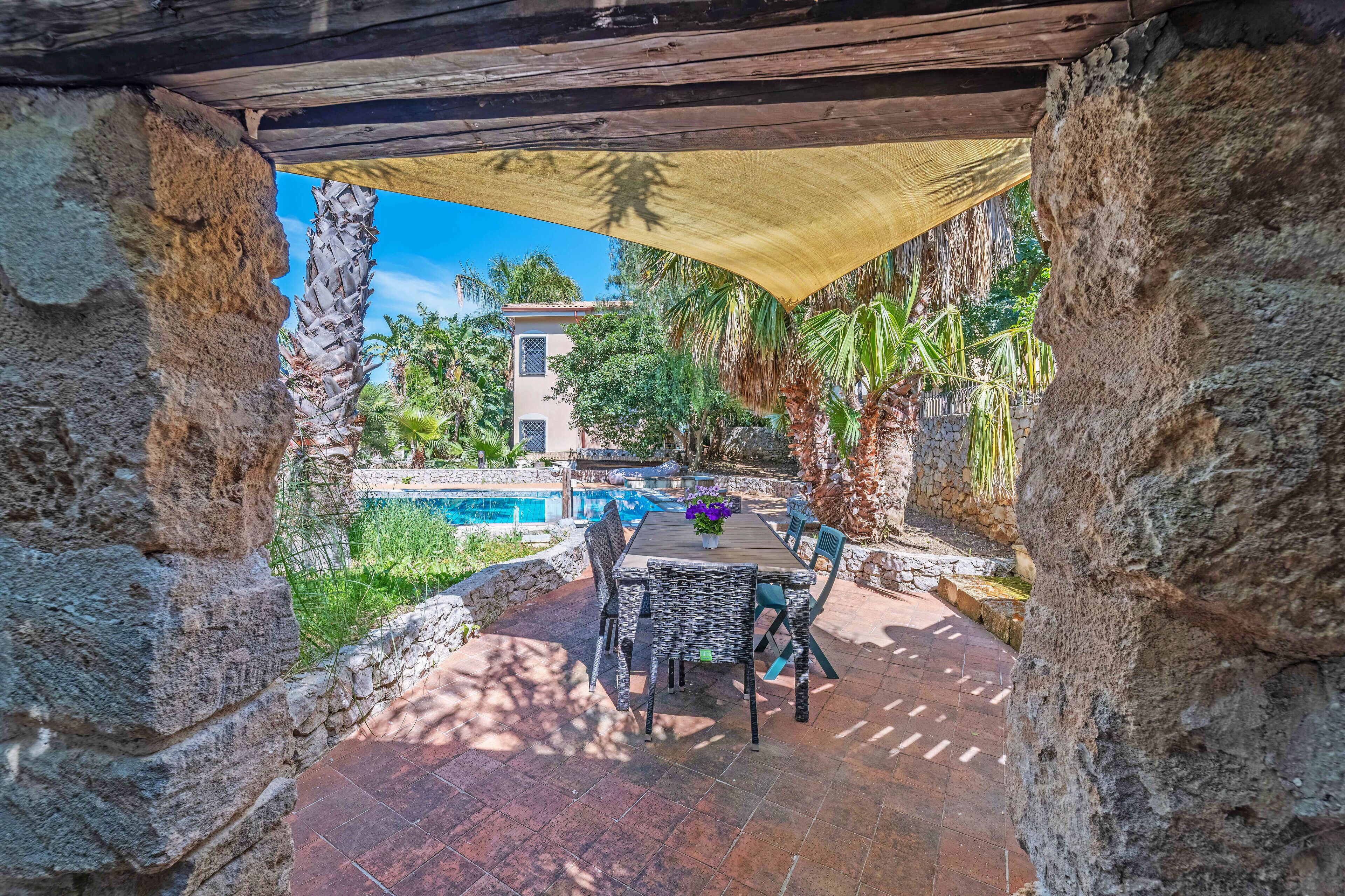 Un patio con piscina, pareti in pietra e mobili da esterno.