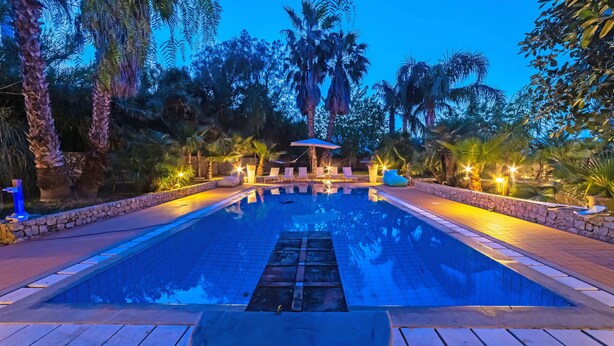 A swimming pool with lounge chairs and a covered seating area surrounded by palm trees. - 600 meters away from the sea, private pool, lush garden (Carini)