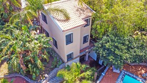 A two-story building surrounded by lush greenery, including palm trees and various shrubs. - 600 meters away from the sea, private pool, lush garden (Carini)