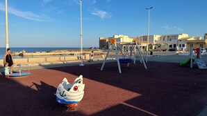A playground with a swing set and a merry-go-round, near a beach with buildings in the background. - 2 Bedroom Villa in Calabernardo (Calabernardo)