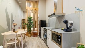 Une cuisine compacte équipée d’un lave-linge, d’une machine à café et d’un coin repas avec une table et des chaises.