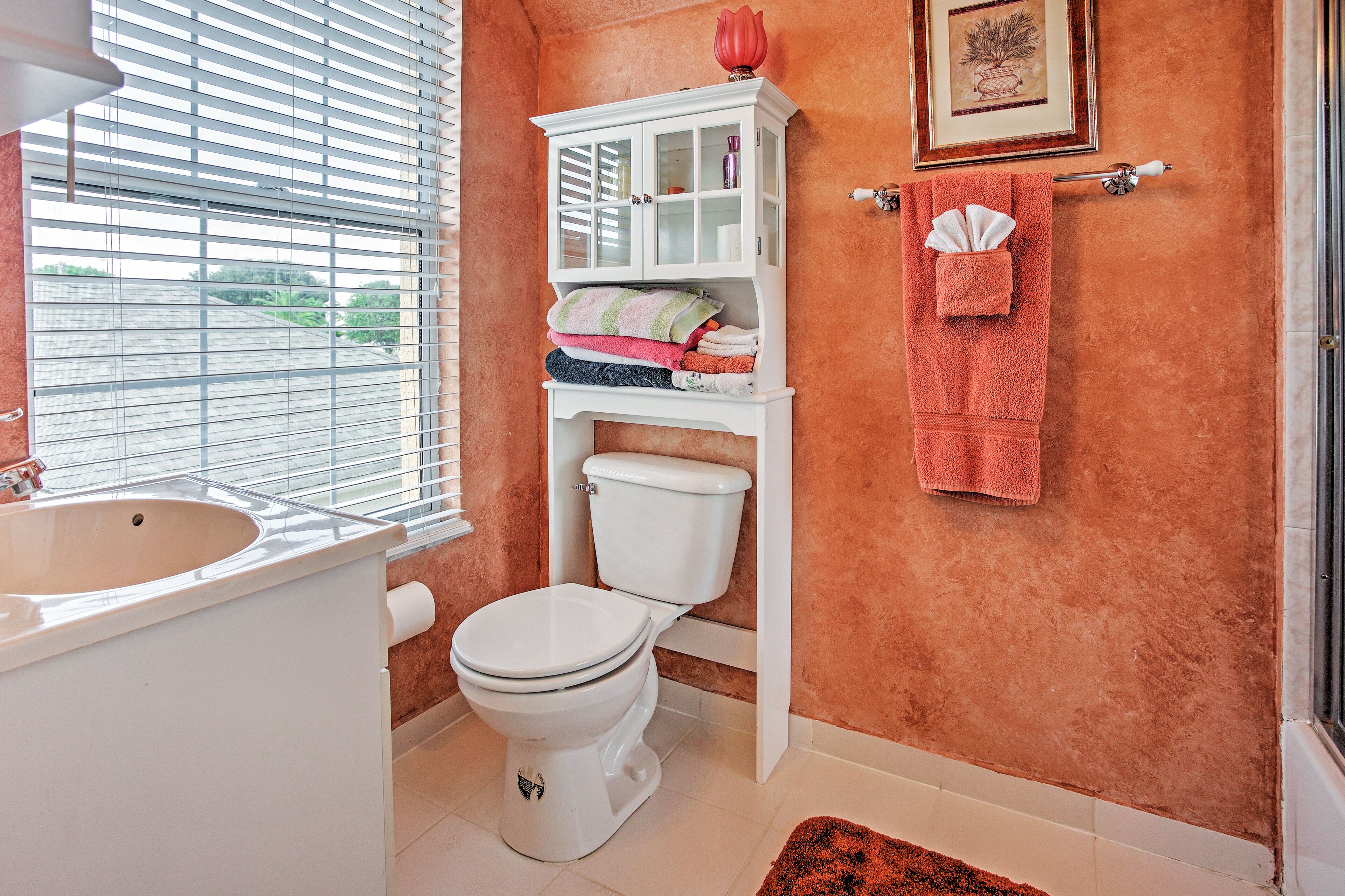 A bathroom with a toilet, a cabinet, a sink, and a towel rack.