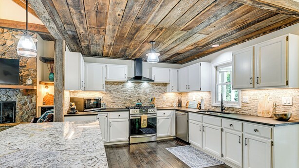 A spacious kitchen with white cabinets, a large island, and a rustic wooden ceiling. - Outdoor Fireplace + Views Mountain Bearadise (Sapphire)