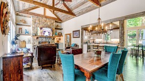 A spacious dining area with a wooden table and teal chairs, a stone fireplace, and a rustic ceiling. - Outdoor Fireplace + Views Mountain Bearadise (Sapphire)