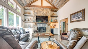 A cozy living room with leather sofas, a stone fireplace, and a television mounted on the wall. - Outdoor Fireplace + Views Mountain Bearadise (Sapphire)
