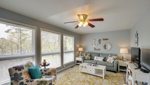 Ein Wohnzimmer mit Deckenventilator, einer Couch, einem Couchtisch und einem Fernseher.