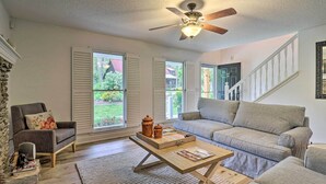 Ein Wohnzimmer mit Sofa, Sessel, Couchtisch und Deckenventilator.