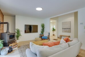 Een moderne woonkamer met een open haard, bank, bijzettafeltje en potplanten.