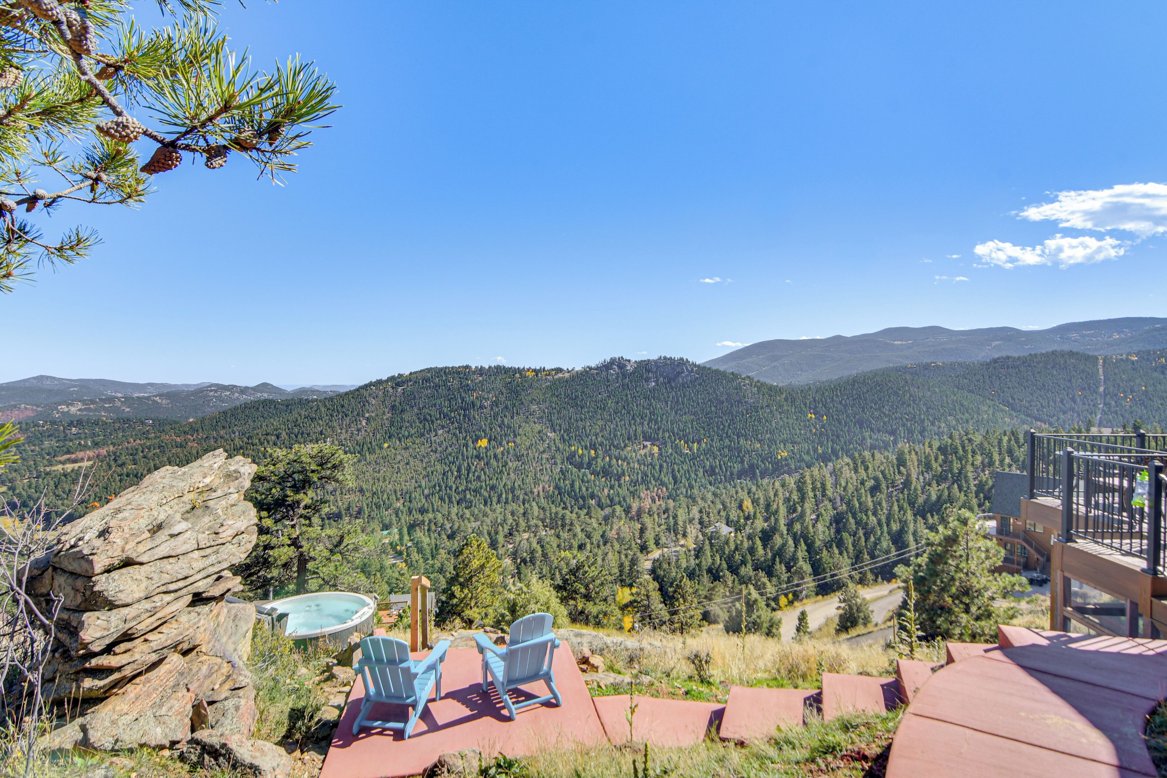 A mountain view with a hot tub, chairs, and a rock formation.