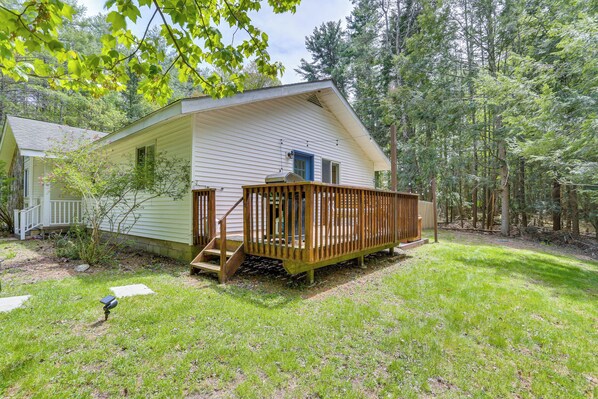 A small, single-story cabin with a wooden deck and a front porch. - Cozy Swan Lake Apt w/ Grill + Private Yard (Swan Lake)