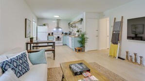 Una sala de estar moderna con un sofá, una mesa de centro y una cocina al fondo.