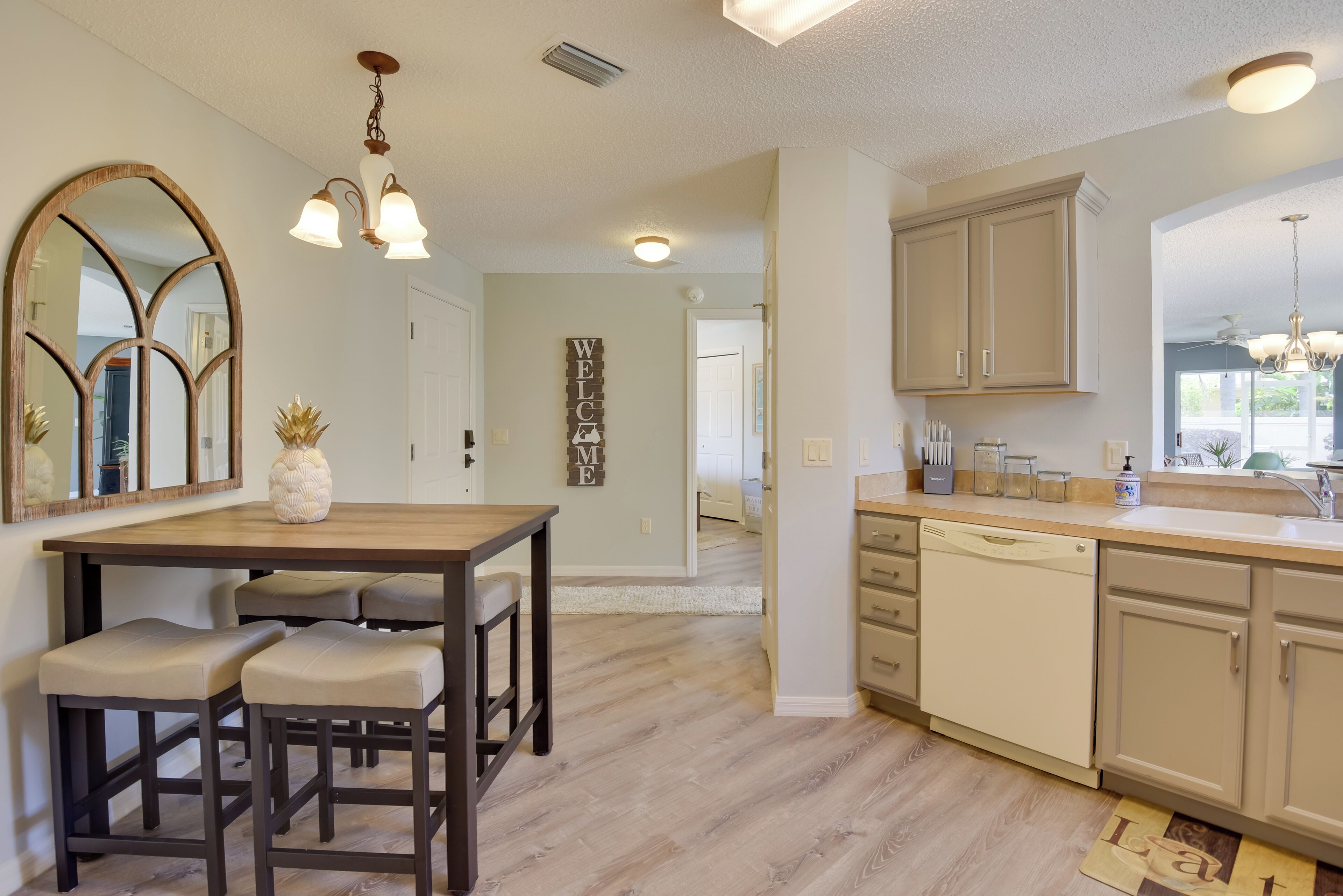 Una cocina moderna con encimeras de madera, lavavajillas integrado y un comedor con mesa y dos sillas de madera.