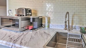 A kitchen with a microwave, toaster, and coffee maker on the counter, a sink with a faucet, and a tiled backsplash. - Spacious Lexington Studio: 2 Miles to Rupp Arena (Lexington)