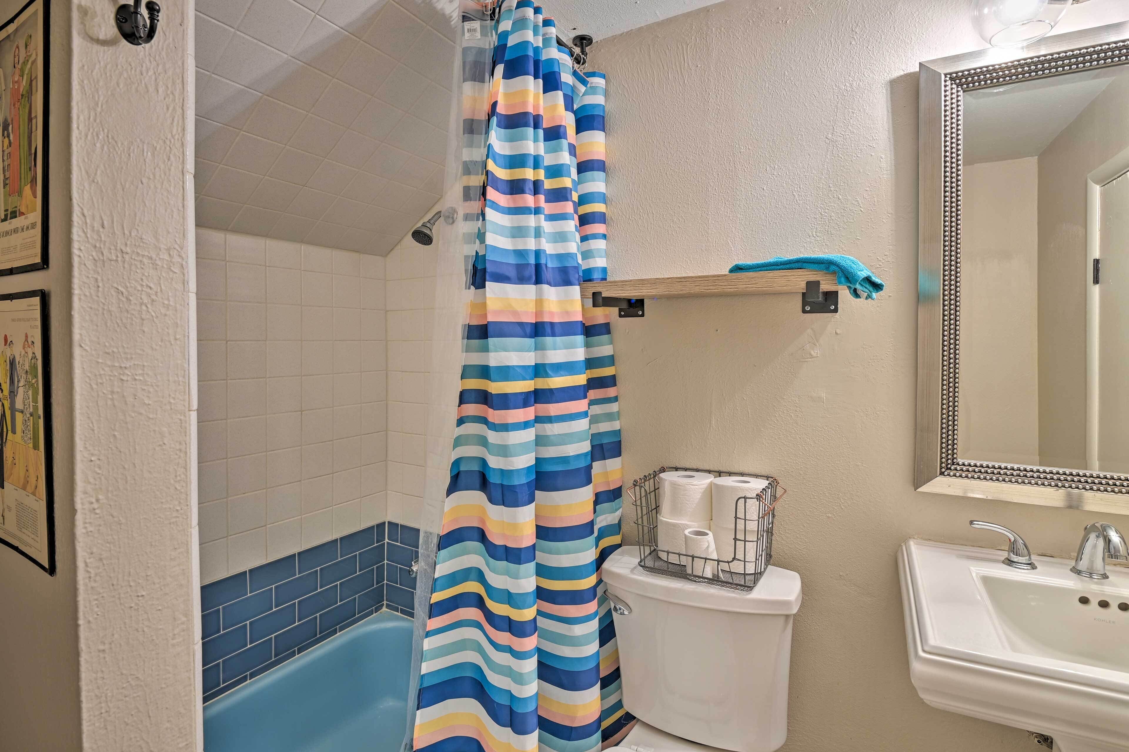 A bathroom with a striped shower curtain, a white sink, and a mirror.