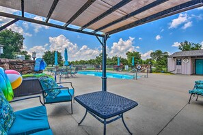 A covered patio area with outdoor seating, a pool, and a small building. - Balcony w/ Hot Tub: Monkey Island Vacation Rental! (Afton)
