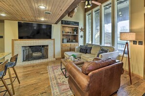 Una sala de estar acogedora con chimenea, un sofá, una mesa de centro y un televisor.