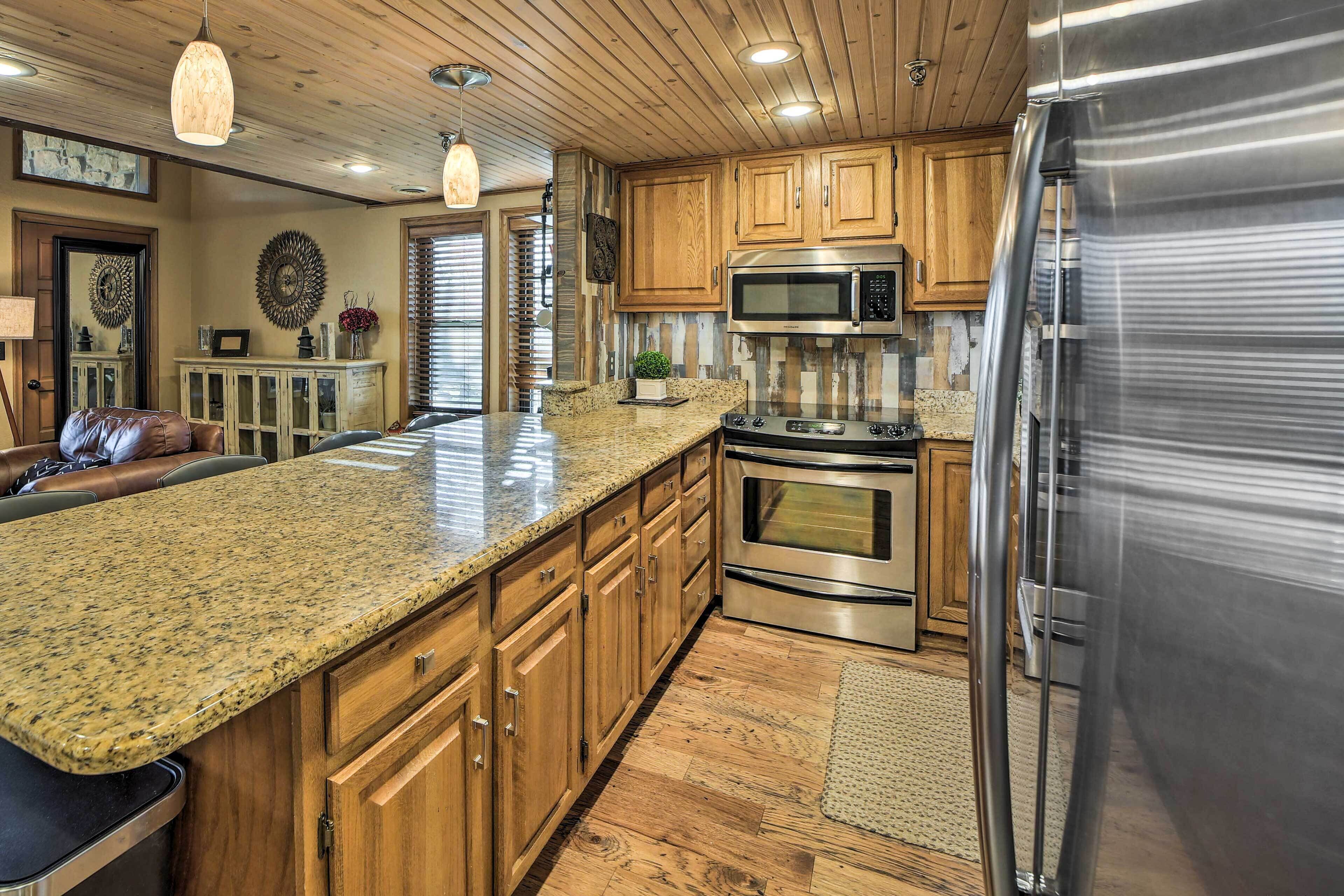 A modern kitchen with granite countertops, stainless steel appliances, wooden cabinets, and a large island.