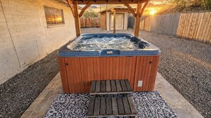 A hot tub under a wooden pergola with a brick wall and a small window. - Havasu Warbler - Hot Tub, BBQ, Parking, FirePit (Lake Havasu City)