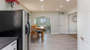 A kitchen with a refrigerator, wooden chairs, a dining table, and a clock on the wall. - Havasu Warbler - Hot Tub, BBQ, Parking, FirePit (Lake Havasu City)