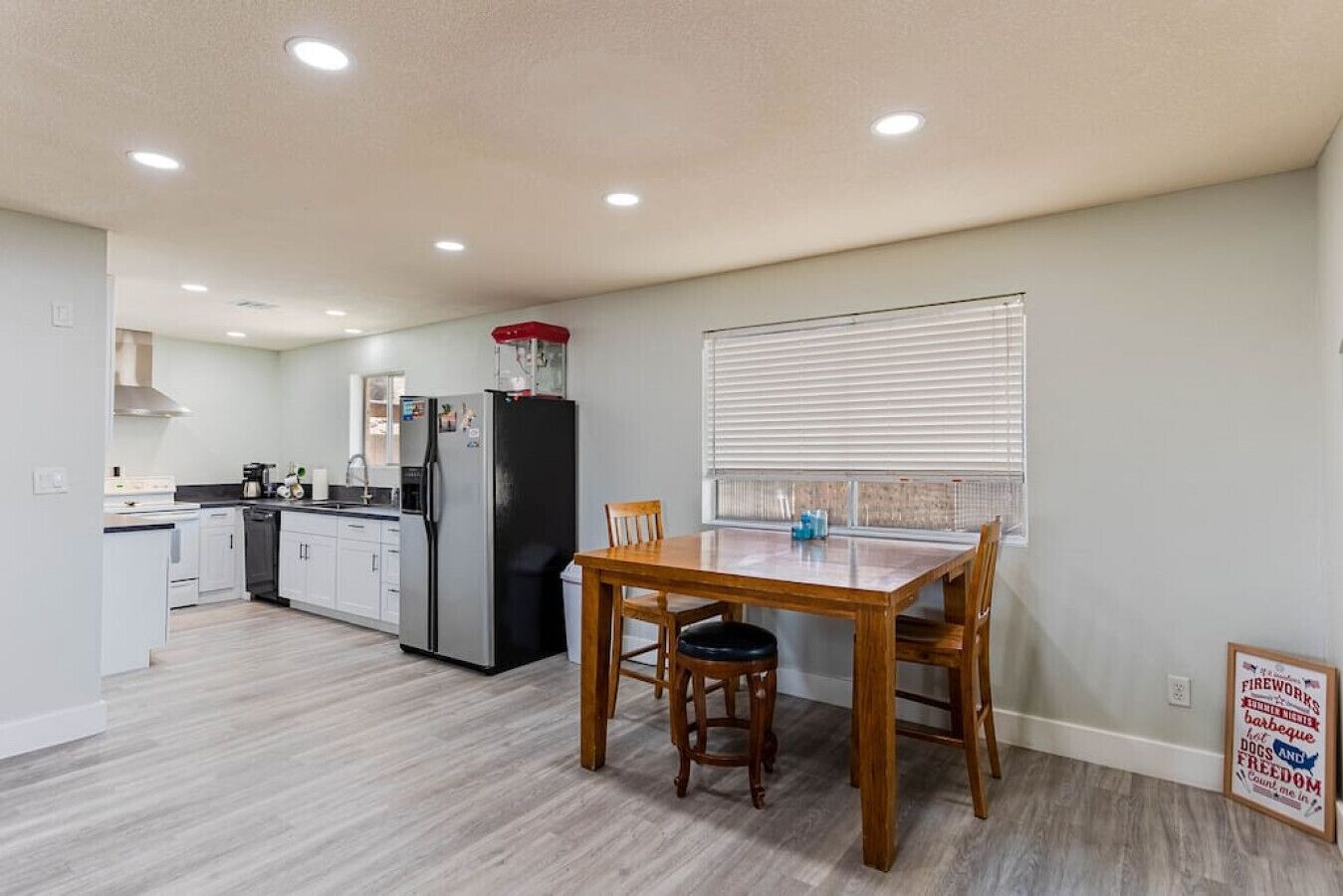 A compact kitchen with white cabinets, a black refrigerator, and a dining table with chairs.