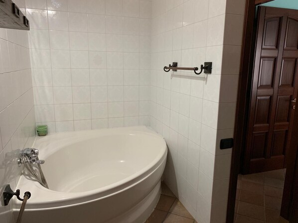 A bathroom with a white bathtub, a green soap dish, and a wooden door.