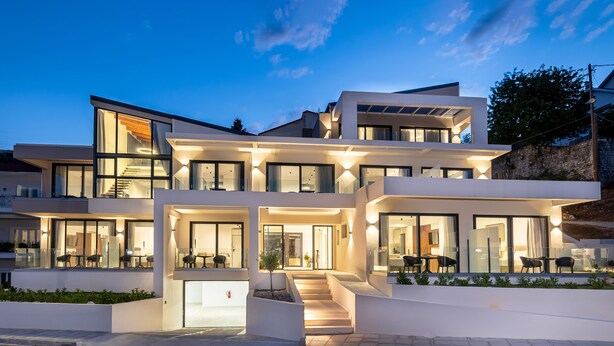 Een modern huis met twee verdiepingen, grote ramen, een trap en buitenmeubilair.