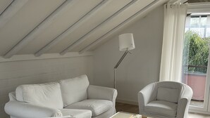 Un salon moderne aux couleurs claires, avec un canapé, deux fauteuils et une table basse.