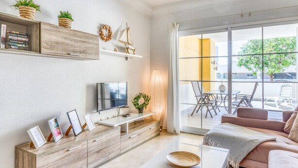 Een moderne woonkamer met een televisie, een houten kast en een bank.