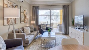A modern living room with a sofa, armchairs, a coffee table, and a TV on a stand. - Beautiful 2-Bedroom Apartment in Estepona with Pool and Terrace (Estepona)