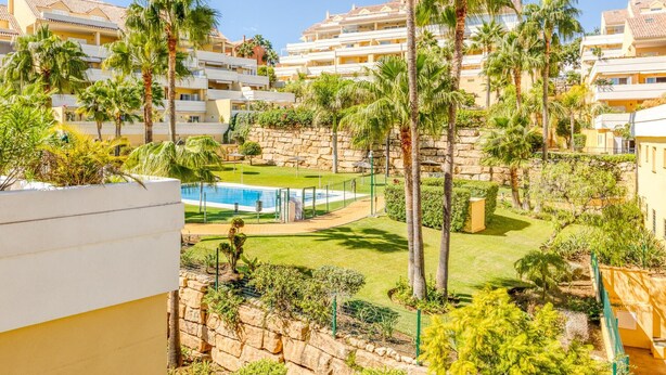 A residential area with multiple apartment buildings, a swimming pool, and palm trees. - Bright 2-Bed Apartment in Estepona's Peaceful Puerto Alto with Pools and Terrace (Estepona)